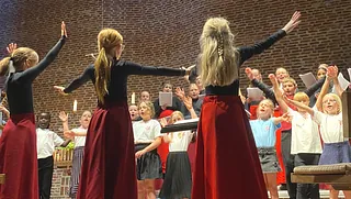 Korpiger med ryggen til laver fagter til et børnekor